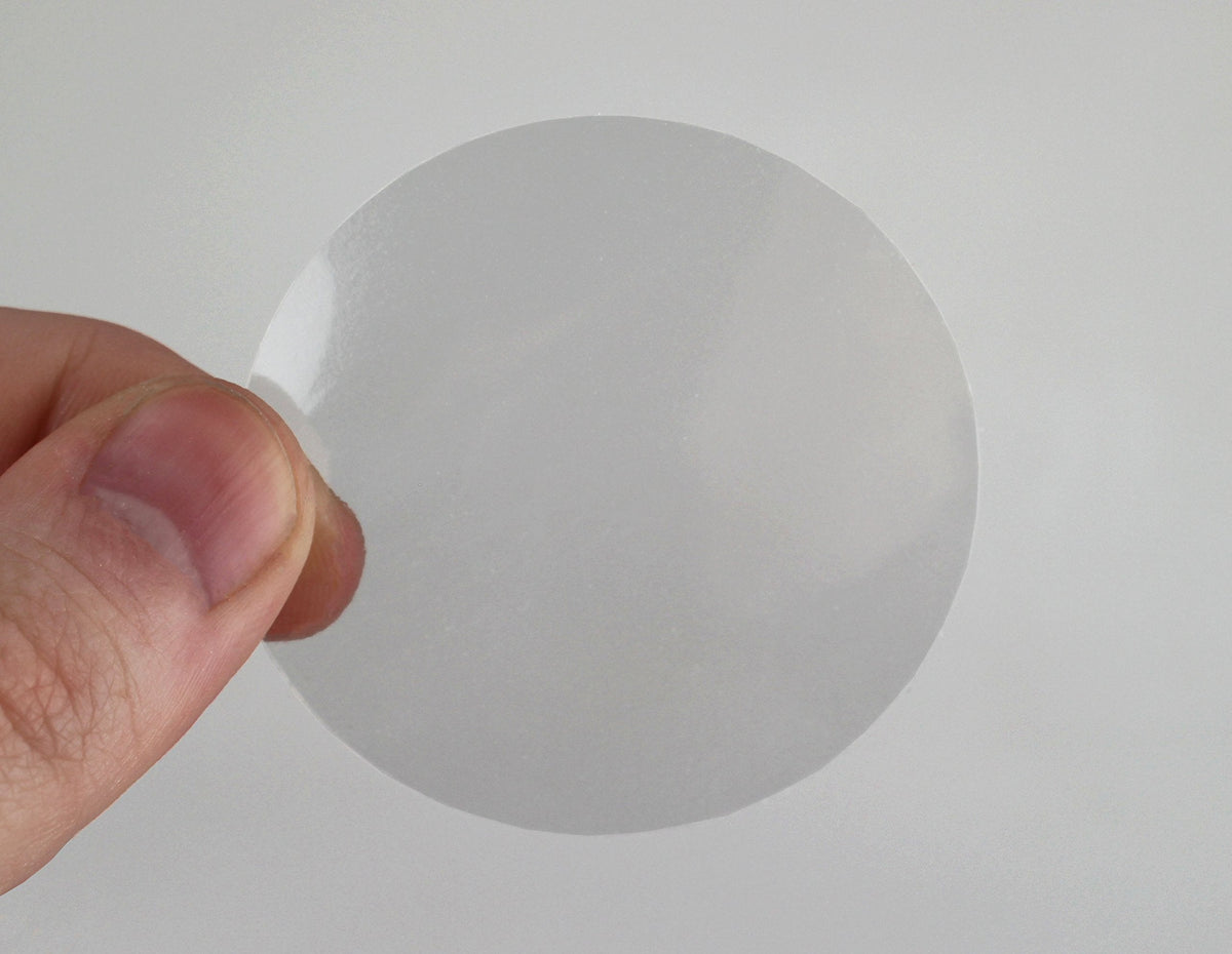 ChromaLabel 2-inch clear round wafer seals on a roll, showing glossy, transparent adhesive seals for packaging or labeling.